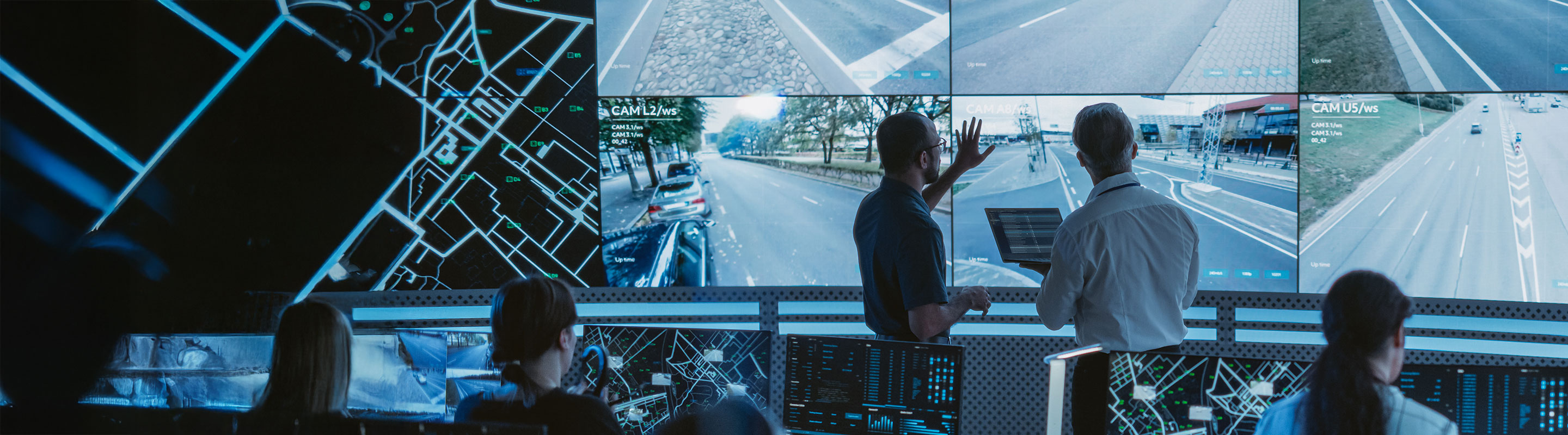 Two professionals analyzing real-time data on large digital screens in a control centre, illustrating advanced IoT connectivity networks for smart infrastructure.