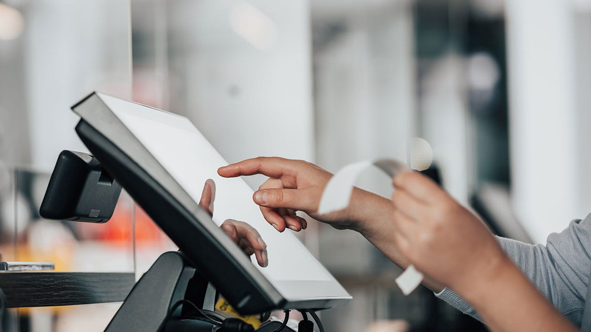 Close-up of hands operating a touchscreen checkout monitor powered by a high-speed 5G retail network.